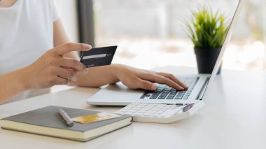 Kredi kartıyla ödemeyi ev telefonuyla, eller plastik kredi kartı tutarak ve dizüstü bilgisayar kullanarak yapıyor. Çevrimiçi alışveriş kavramı. 