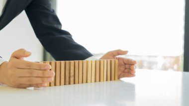 İş hayatında planlama, risk ve stratejiye yakın bir bakış açısı. Bir iş adamı masaya tahta bir taş koyar ve onu korur.