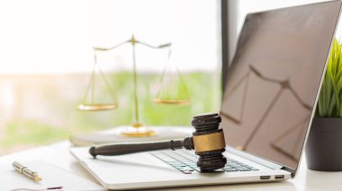 Yargıcın çekici dizüstü bilgisayarda, altın pullar da avukatın masasında kağıt ve kalemlerle duruyor..