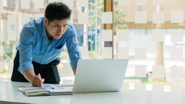 Ofiste çalışan bir iş adamı. Bilgisayarı ve grafik veri tabloları ve hesap makineleri. Masanızda hesaplamak ve analiz etmek için..