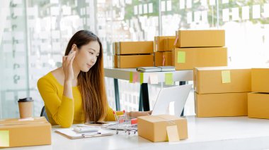 Ev Kutusu Smartphone Laptop Çevrimiçi Pazarlama Paket Taşıma Konsepti E-ticaret kavramından çalışan Asyalı genç kadının küçük işletme KOBİ Serbest Çalışan Portresi