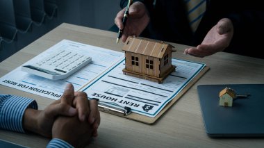 Satış temsilcileri ev satın alma sözleşmeleri sunar veya kredi ve faiz oranlarını, ev satın alma ve kiralama fikirlerini tartışırlar.