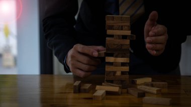 İnşaat işi risk konsepti, iş adamı masadaki tahta blokları koruyor