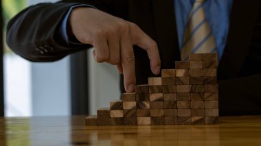 İş geliştirme konsepti işadamı eli masanın üzerinde tahta blok merdiveni üzerinde yürüyor