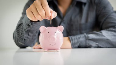 Domuz kumbarasında bozuk para tutan genç işadamı, para biriktirme konsepti evet gelecek