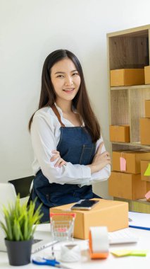 Küçük işletme girişimi, KME sahibi, Asyalı bayan girişimci okuyun ve sipariş numarasını dizüstü bilgisayara yazın. Müşterilere satılan kutuları hazırlamak için çevrimiçi siparişleri kontrol et. Çevrimiçi KOBİ iş fikri.