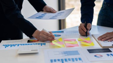 İş adamlarının bir toplantıda grafikleri analiz ederek belgeleri ve fikirleri tartışmaları..