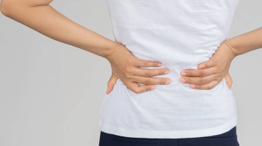 Beyaz arka plan medikal konsepti üzerinde duran bel ağrısı olan genç bir kadının arka planı .