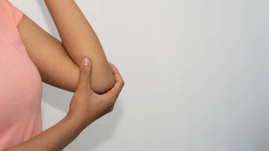 Dirseğinde ağrı olan ve elini sıkan genç bir kadın tıbbi bir kavramı tutuyor.