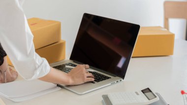 İş Mutlu Asyalı Kadın KOBİ Çevrimiçi Bilgisayarı Kullanarak Ev Ofisi 'nde paket kutuları, online iş fikirleri ve Coronavirus salgını sırasında teslimatlar ile müşteri siparişleri alın.