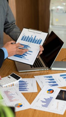 Hesap makinesi kullanarak grafik analizi yapan Asyalı bir finans subayının portresi. Yatırım sonuçları ofisteki masada. finansal muhasebe kavramı