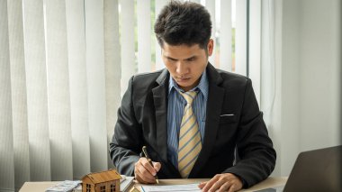 İşadamlarının elleri, emlak ve emlak alımına yatırım yapmak için faiz, vergi ve kazancı hesaplar..