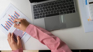 Finansal grafiği olan bilgisayar ve hesap makinesi kullanan kadın muhasebeci ve en üst görünüm masasındaki ev ofis giderlerini hesapla.