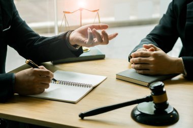 İş adamı ve avukat bir masada oturmuş sözleşmeli belgeleri tartışıyorlar. Yasal fikirler, tavsiyeler, ortak avukat veya avukatla yapılan anlaşmalar, sözleşmeli anlaşmaları tartışıyorlar..