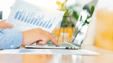 İş adamı dizüstü bilgisayarda çalışıyor ve ev harcamaları üzerindeki finansal grafikleri analiz ediyor