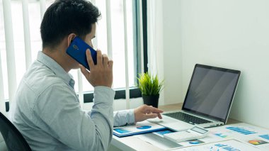 İş adamı dizüstü bilgisayarda klavye yazıyor ve internet konsept çalışma tablosu üzerinde grafik kağıtları ile çağrı sözlüğünde konuşuyor.