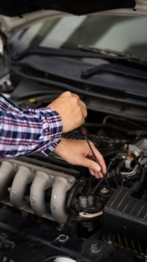 Arabasının motorunu kontrol eden ve bakımını yapan genç bir adam. Kaputu aç, uzun mesafe sürmeden önce motor güvenliğini kontrol et.,