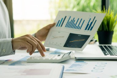 Pens ve grafik dokümanlı bilgisayar kullanan muhasebeci, masa başında çalışan iş adamı hesap makinesi kullanarak numaraları ve finansal muhasebe kavramlarını hesaplıyor..