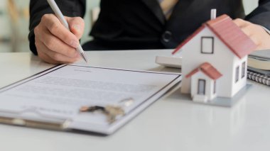 İş adamı ya da ev satış temsilcisi sözleşme belgeleri ve dizüstü bilgisayarlı hesap makineleriyle çalışıyor. Gayrimenkul yatırımları ve ev alımları için faiz, vergi ve kârın hesaplanması.