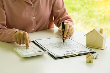 İş adamı ya da ev satış temsilcisi sözleşme belgeleri ve dizüstü bilgisayarlı hesap makineleriyle çalışıyor. Gayrimenkul yatırımları ve ev alımları için faiz, vergi ve kârın hesaplanması.