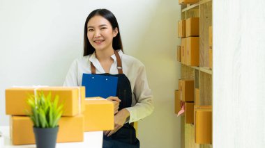 Küçük bir işletme kuran KOBİ sahipleri, Kadın Girişimciler, kutuları hazırlamak için çevrimiçi siparişleri kontrol etmek üzere kutular ve dizüstü bilgisayarlarla çalıştılar. Müşterilere satıyorum. Çevrimiçi KOBİ iş fikri.