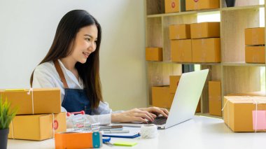 Küçük bir işletme kuran KOBİ sahipleri, Kadın Girişimciler, kutuları hazırlamak için çevrimiçi siparişleri kontrol etmek üzere kutular ve dizüstü bilgisayarlarla çalıştılar. Müşterilere satıyorum. Çevrimiçi KOBİ iş fikri.