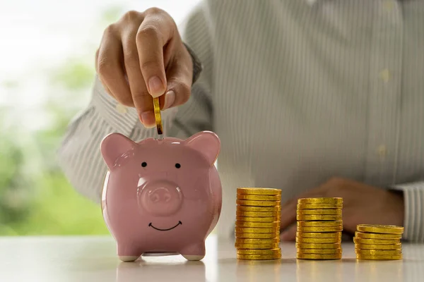 woman holding a coin in a glass jar Close-up of young woman putting gold coins in a jar. Planning, investing and saving ideas.