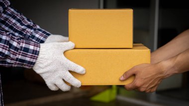 Beyaz eldivenli genç teslimatçı evin önünde kutu tutuyor, online teslimat konsepti..