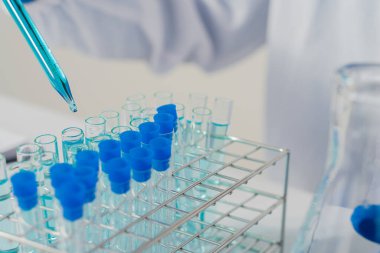 Deney tüpü tutan profesyonel bir bilim adamı ya da araştırmacı pipetin numunesini test tüpünün içine indirir. Virüs analizi ile Corona COVID-19 yakın dönem bilimsel laboratuvar testinde