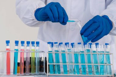 Deney tüpü tutan profesyonel bir bilim adamı ya da araştırmacı pipetin numunesini test tüpünün içine indirir. Virüs analizi ile Corona COVID-19 yakın dönem bilimsel laboratuvar testinde