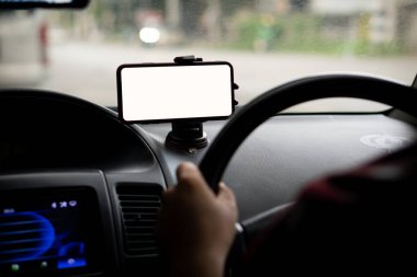 Genç adam GPS konseptli bir arabada beyaz ekranlı bir telefon tutuyor.