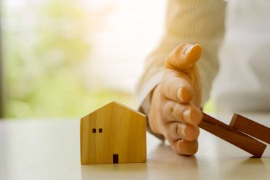İş adamının eli, tahta bloklar, güvenlik yatırımları ve emlak ve mülkiyet sigortasıyla ev risklerini durdurur