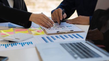 Bir grup işadamı elinde kalemle şirketin büyüme projesinin başarısını tartışıyor. Finansal istatistik profesyonel yatırımcısı, bir grafik belgesi ve ofis hesap makineli bir laptop ile stratejik bir plan üzerinde çalışıyor..