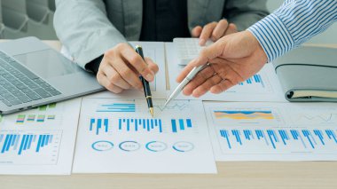 Bir grup işadamı elinde kalemle şirketin büyüme projesinin başarısını tartışıyor. Finansal istatistik profesyonel yatırımcısı, bir grafik belgesi ve ofis hesap makineli bir laptop ile stratejik bir plan üzerinde çalışıyor..