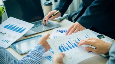 Bir grup işadamı elinde kalemle şirketin büyüme projesinin başarısını tartışıyor. Finansal istatistik profesyonel yatırımcısı, bir grafik belgesi ve ofis hesap makineli bir laptop ile stratejik bir plan üzerinde çalışıyor..