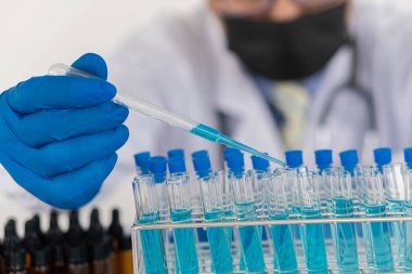 Asyalı bilim adamları laboratuvar deneyleri yapıyor. Pipet numuneyi yakın çekim test tüpüne indiriyor..