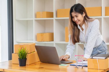 Girişim, küçük işletme, KOBİ, kutularla çalışan Asyalı kadın girişimcilerin sahibi. Gülümse ve bilgisayar kullanarak satış açığını kontrol et. Çevrimiçi KOBİ işinde farklı düşünmeyi başardıktan sonra.
