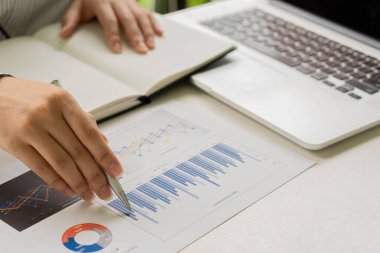 Raporlar, hesaplamalar, ev finansmanı, yatırım, ekonomi, tasarruf veya ofis sigortası fikirleri yapmak için gelir ve gider hesaplayıcıları, hesaplar veya mali denetçiler kullanarak grafik kağıtları ve dizüstü bilgisayarlar üzerinde çalışan bir işadamı.