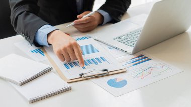 Raporlar, hesaplamalar, ev finansmanı, yatırım, ekonomi, tasarruf veya ofis sigortası fikirleri yapmak için gelir ve gider hesaplayıcıları, hesaplar veya mali denetçiler kullanarak grafik kağıtları ve dizüstü bilgisayarlar üzerinde çalışan bir işadamı.