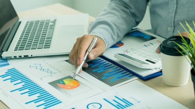 Raporlar, hesaplamalar, ev finansmanı, yatırım, ekonomi, tasarruf veya ofis sigortası fikirleri yapmak için gelir ve gider hesaplayıcıları, hesaplar veya mali denetçiler kullanarak grafik kağıtları ve dizüstü bilgisayarlar üzerinde çalışan bir işadamı.