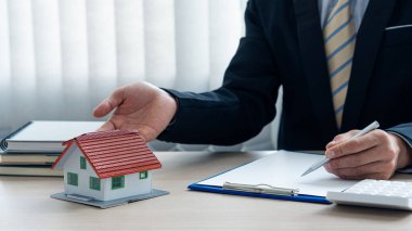 Emlakçılarla ev planları ve hesap makinesi ve dizüstü bilgisayar sigorta konsepti veya emlak kredileriyle ev satın alma sözleşmesi belgeleri