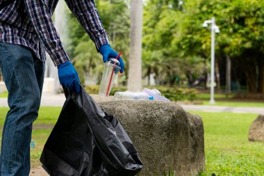 Gönüllüler hayır işi için çevresel atıkları toplamaya yardım ediyorlar. Adam plastik şişe topluyor dünyadaki çöpleri topluyor, ormanı temizliyor. Kamu bahçesinden çöp toplamaya yardım et.