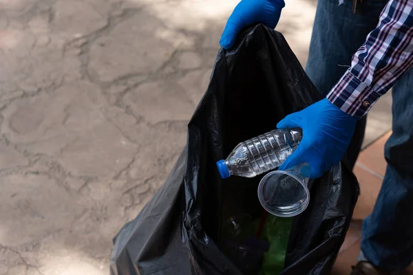 Gönüllüler hayır işi için çevresel atıkları toplamaya yardım ediyorlar. Adam plastik şişe topluyor dünyadaki çöpleri topluyor, ormanı temizliyor. Kamu bahçesinden çöp toplamaya yardım et.