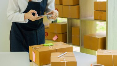 Küçük bir işletme sahibi, iş yerinde karton kutuları fotoğraflayan genç bir kadın. Küçük işletme girişimcisi, KOBİ veya Evde Bir Kutuyla Çalışan Serbest Asyalı Kadın, Çevrimiçi Teslimat Fikirleri