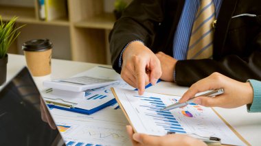 Finans müdürü, şirketin büyüme projesinin başarısını tartışmak için toplandı. Hesap makinesi ve dizüstü bilgisayarlı grafik analiz kalemi tutan iki işadamı vergi finans konsept ofisinde masa başında.