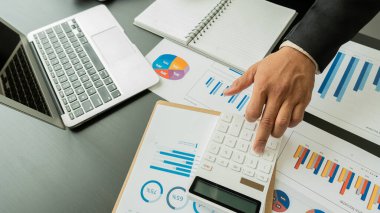 Şirketin mali sonuçlarının hesaplanması, hesap makinesi ve grafik dökümanının ofis ve işletme vergisi hesaplamalarındaki ahşap bir tabloda üst görünümü
