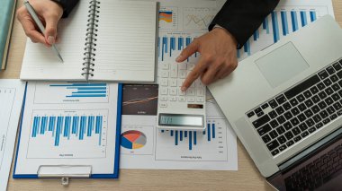 Şirketin mali sonuçlarının hesaplanması, hesap makinesi ve grafik dökümanının ofis ve işletme vergisi hesaplamalarındaki ahşap bir tabloda üst görünümü