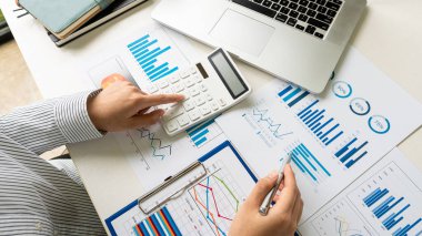 Şirketin mali sonuçlarının hesaplanması, hesap makinesi ve grafik dökümanının ofis ve işletme vergisi hesaplamalarındaki ahşap bir tabloda üst görünümü