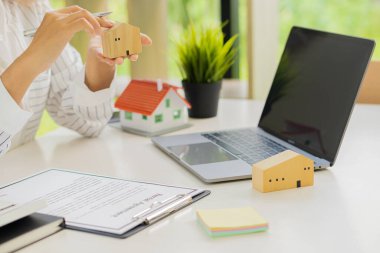 İş adamı veya ev satış temsilcisi, satış ve kira için faiz, vergi ve kârı hesaplamak için sözleşme belgeleri ve dizüstü bilgisayarla çalışır..