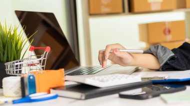 Ev masasında paket kutusu, KOBİ iş fikri, çevrimiçi satış ve teslimat ile birlikte dizüstü bilgisayarda çalışarak Bağımsız Asya İş Dünyası alışverişi başlatılıyor.